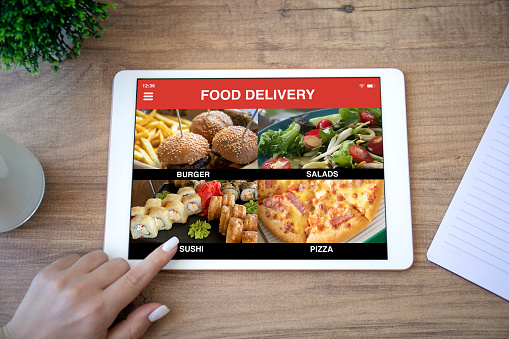 female hand selects menu on computer tablet with food delivery application on the screen