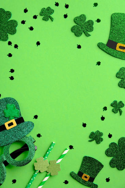 istock St Patricks Day vertical banner design with Irish elf hats, shamrock four-leaf clovers, Patricks day glasses, drinking straws, confetti on green background. St Patricks Day greeting card template. 1303811012