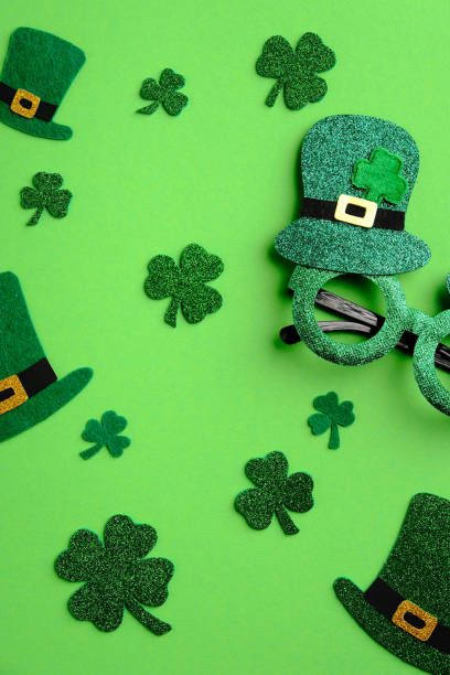 istock St Patricks day flat lay composition. Top view shamrock four leaves clover, leprechaun hats and Patricks day glasses on green background. Saint Patrick's day greeting card mockup. 1303811017