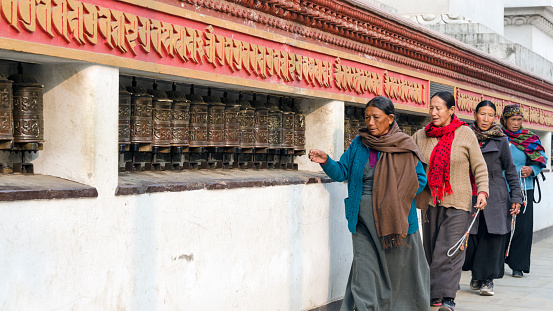 Kathmandu, Nepal - February 16, 2015: Women at the mani wall at Swayambhunath or Monkey temple, rolling prayer wheels, Kathmandu, Nepal