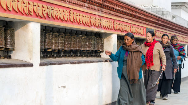 Women at the mani wall at Swayambhunath, rolling prayer wheels, Kathmandu Kathmandu, Nepal - February 16, 2015: Women at the mani wall at Swayambhunath or Monkey temple, rolling prayer wheels, Kathmandu, Nepal prayer wheel nepal kathmandu buddhism stock pictures, royalty-free photos & images