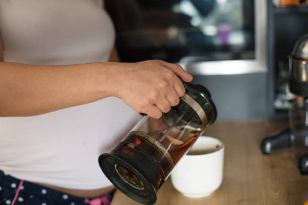 istock Pregnant woman in kitchen pour coffee. 1303811789