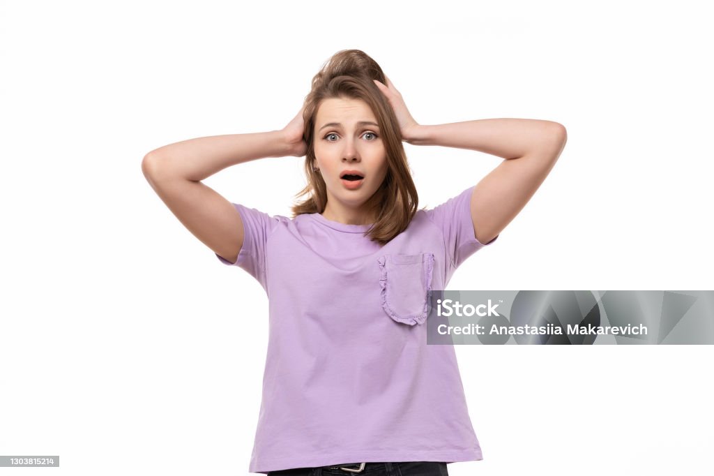 Portrait of worried and anxious girl, grab head and panicking, staring alarmed, dont know what do Portrait of concerned, worried and anxious brunette girl, grab head and panicking, staring alarmed, feel scared and nervous, dont know what do. Studio shot, white background Terrified Stock Photo
