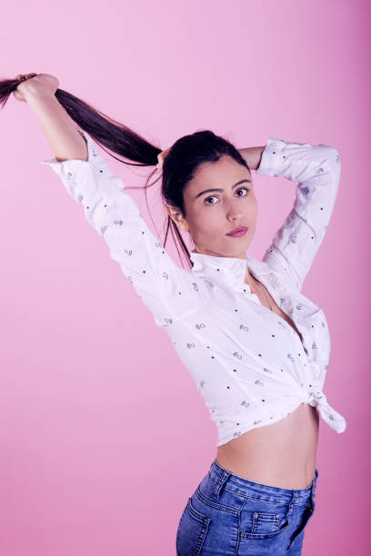 istock woman with white top on pink background 1303815860