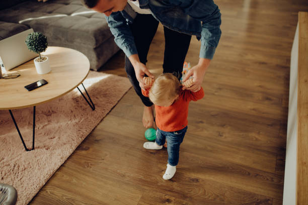 young father is playing with his baby in the living room stock photo