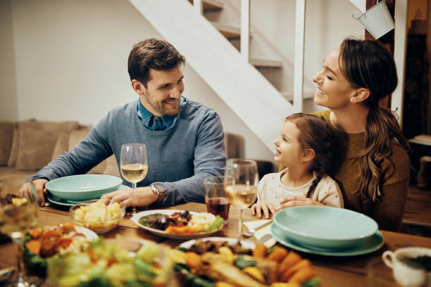 istock Happy family talking while eating lunch at dining table. 1303822920