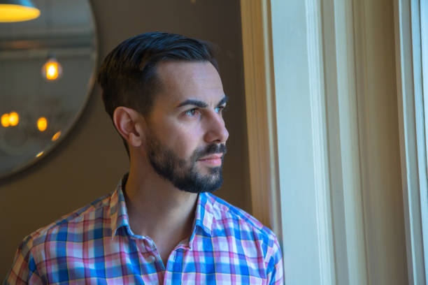 istock A man with a black beard looks thoughtfully out the window 1303824386