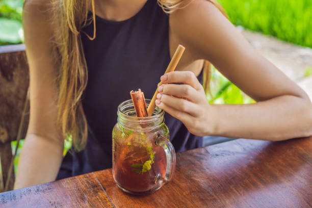 Young woman drinking cold tea with cinnamon in rice field.