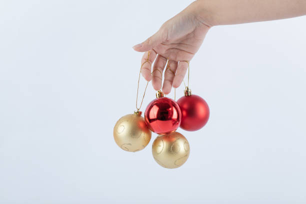 istock Female hand holding Christmas baubles on white background 1303826280
