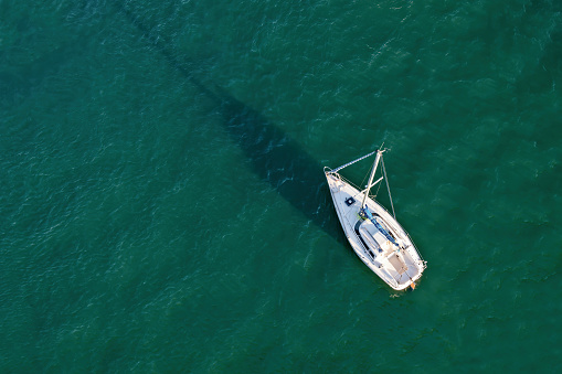Aerial drone view of a sailing boat on emerald water