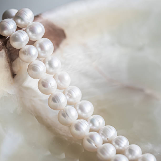 istock Nature white string of pearls on marble background in soft focus, with highlights 1303828486