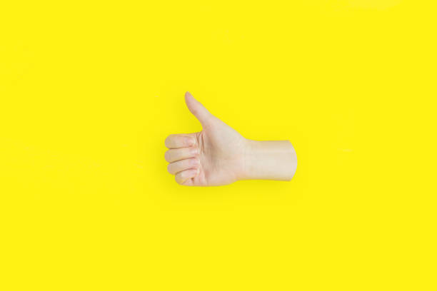 istock Hand showing a thumb-up gesture on yellow background. 1303835499