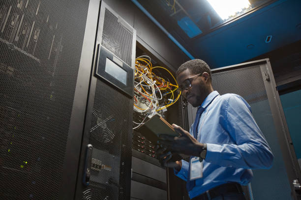 ingeniero afroamericano de redes en la sala de servidores - high speed technology cable computer network fotografías e imágenes de stock