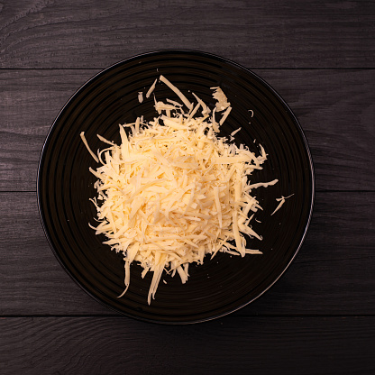 Grated hard cheese on a dark background.