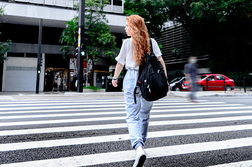 A red-haired woman crossing the street -