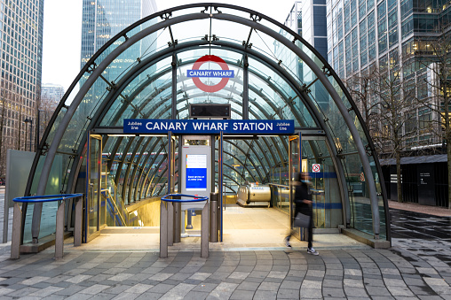 London, UK - 22 February, 2021: color image depicting blurred motion of a commuter outside the modern architecture of Canary Wharf train station in London, UK.