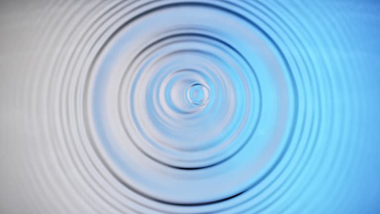 SLO MO LD A droplet creating a splash and concentric ripples when hitting the silver and blue coloured  surface