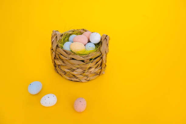 istock Easter holiday decorations on yellow background. Colorful easter painted speckled eggs in basket. Creative spring composition with Easter elements - flowers and eggs. Traditional Easter Celebrating 1303841588