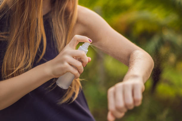 Woman spraying insect repellent on skin outdoor stock photo
