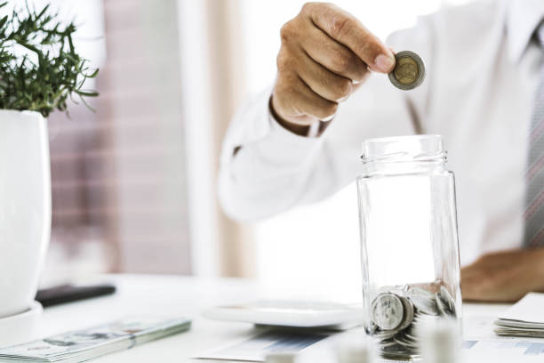 istock Businessman putting coins into a glass jar. 1303842797