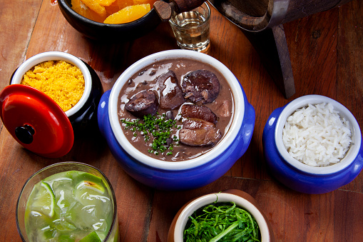 Brazilian Feijoada, traditional food with various pork meats accompanied with cabbage, rice, caipirinha, farofa