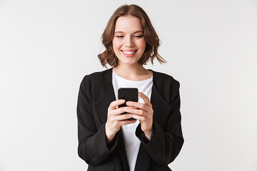 Image of cheerful young woman standing isolated chatting by mobile phone looking aside.