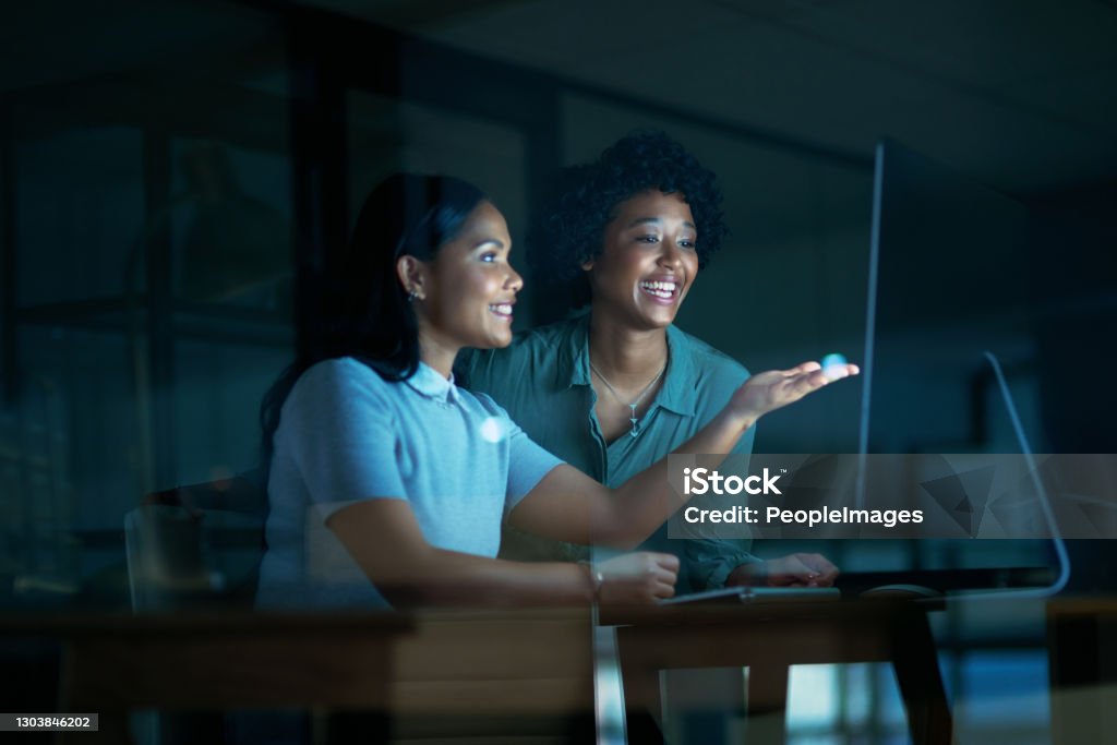 Who said the night was for sleeping? Shot of two young businesswomen using a computer together during a late night at work Computer Programmer Stock Photo