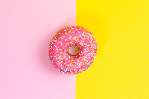 istock Round doughnut with pink icing. Pink and yellow background. Copy space. Flat lay 1303846529