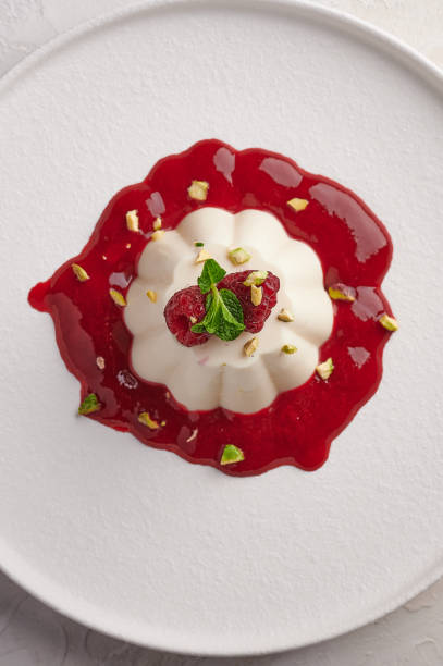 istock Vertical orientation panna cotta with raspberry syrup, pistachios, berries and mint 1303849397
