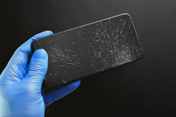 istock A broken touch phone with a cracked screen in your hand on a black background. 1303849616