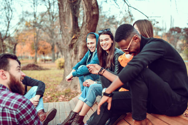 istock Park Fun And Enjoyment For Cute Multiethnic Friends Sitting On Bench 1303851330