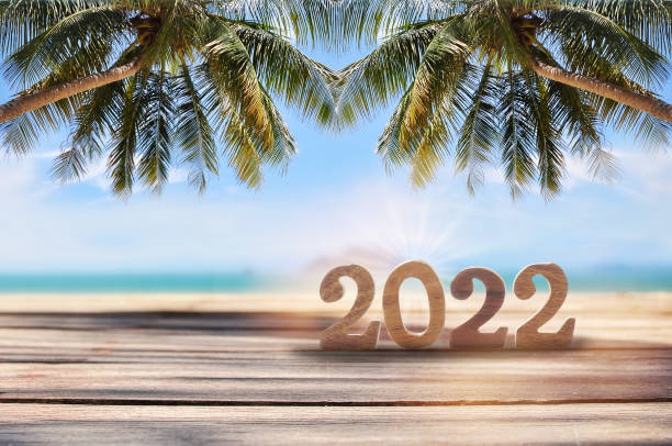 istock 2022 written on wooden cube on planks on tropical beach background 1303853955