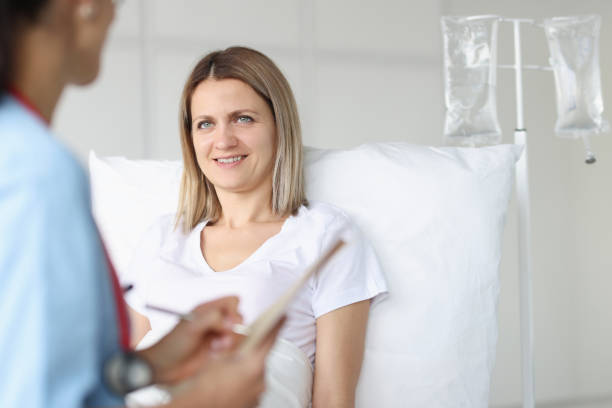 Doctor examining woman lying on bed in hospital Doctor examining woman lying on bed in hospital. Infusion therapy concept infused stock pictures, royalty-free photos & images