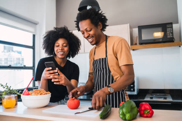 istock Afro couple cooking together and using phone at home. 1303855741