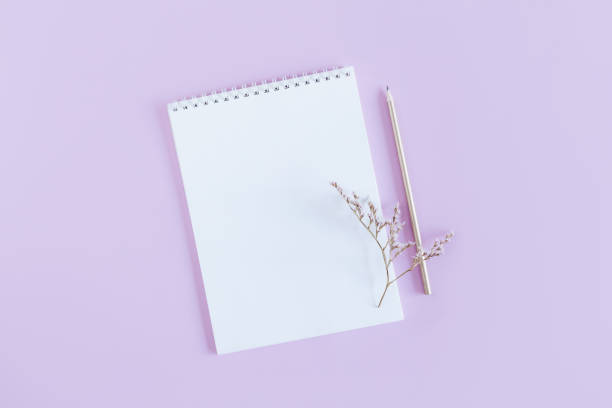 istock Notebook with blank page and pencil on a violet pastel background. 1303855765