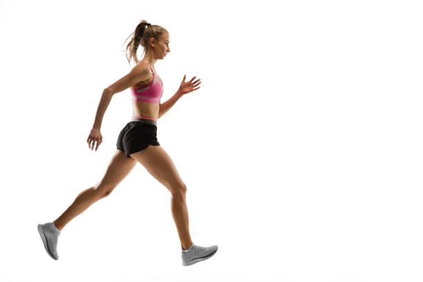 Profile of a runner girl running at sunset in the mountain with a warm orange light