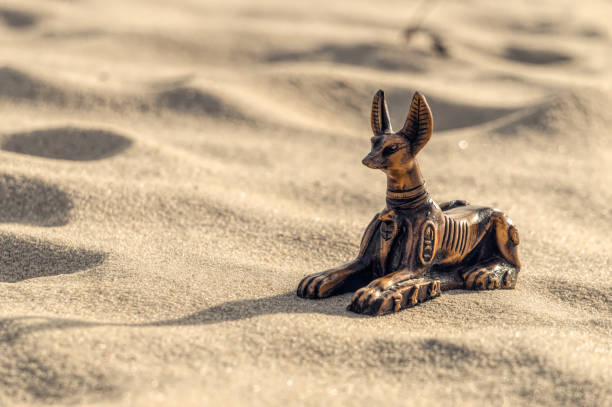 Ceramic statuette of the Egyptian god Anubis against the backdrop of sunny sands Traditional souvenir. An intaglio ceramic figurine of the ancient Egyptian god of death Anubis, half-sherk-half lion against the backdrop of the hot sands of the Sahara Desert in North Africa. Tourist trip to the sights of Egypt traditional sun symbol art for sale stock pictures, royalty-free photos & images