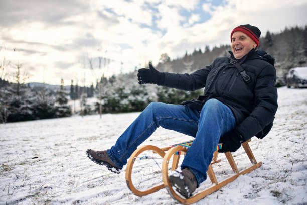 This enchanting stock photo showcases a wooden sled with a blue seat, captured from an aerial perspective in the snow. The wintry scene evokes a sense of joy and adventure.\n\nThe wooden sled rests nestled in a fresh, untouched blanket of snow. The vibrant blue seat creates a striking contrast against the white winter landscape. The top-down view offers an inviting glimpse of the sled, reminiscent of carefree sledding adventures.\n\nThis image is perfect for conveying winter ambiance, family fun, and nostalgic memories. It is ideal for winter and holiday projects, snow event announcements, or illustrating winter leisure activities. This photo is guaranteed to bring a smile to your target audience's faces and create an inviting atmosphere.