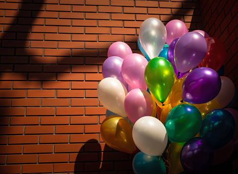 Holiday concept. Bunch of colorful balloons on a brick wall background