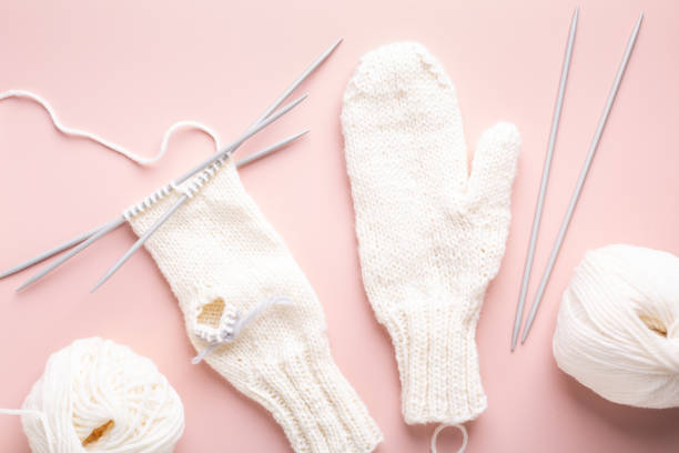 istock White wool knitting needles and mittens in the knitting progress on pastel pink background. Female hobby. Top view 1303870561