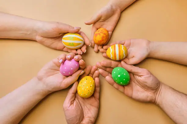 Colorful easter wooden eggs in hands of a friendly family after egg-hunt