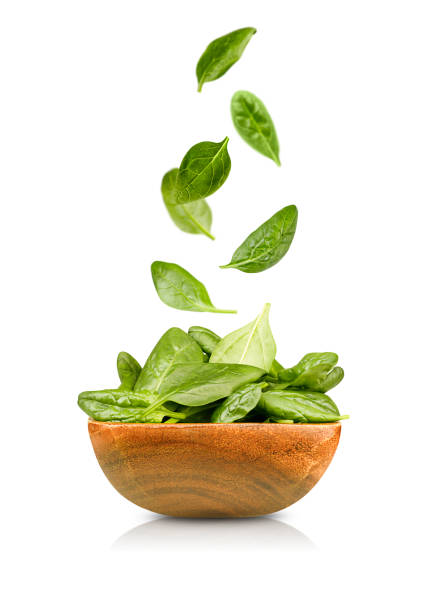 fresh spinach falls into the plate isolated spinach leaves falling into a wooden plate. isolated on white background spinach stock pictures, royalty-free photos & images