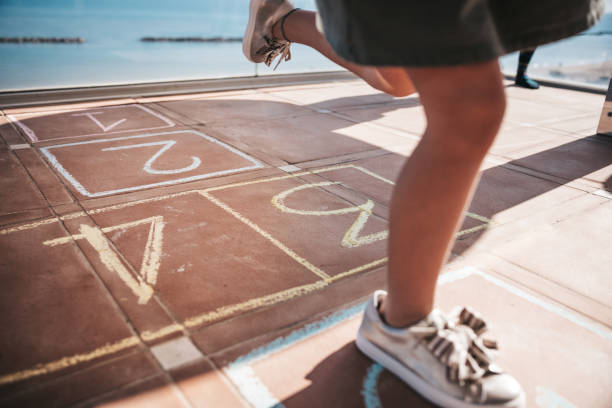 Cute and gorgeous child playing in the school yard jumping on a hopscotch.