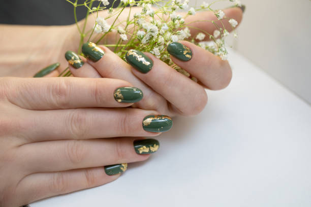 Hands with beautiful khaki manicure and gold foil.