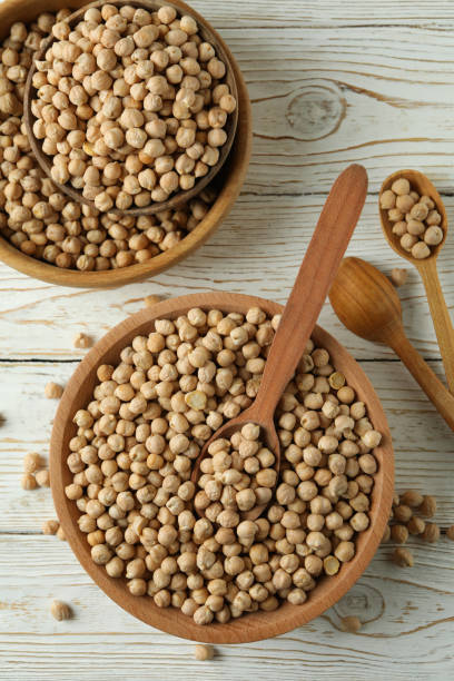 istock Bowls and spoons with chickpea on white wooden table 1303878718