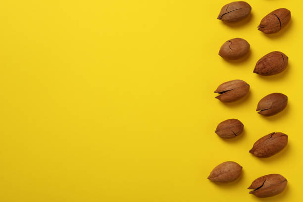 istock Tasty pecan nuts on yellow background, space for text and top view 1303879164