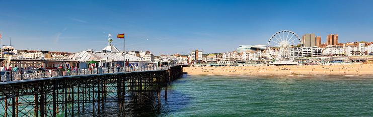 BRIGHTON, UK - JUN 5, 2013: Beachfront panoramic view with the Ferris Wheel promenade and shingle beach pictured from the Brighton Palace Pier on a sunny summer day