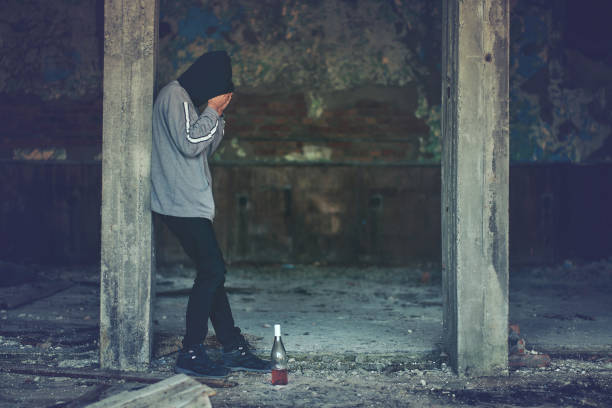 istock Desperate young man standing in ruined building and drinking alcohol 1303881276