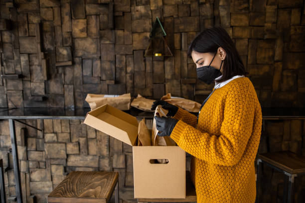 istock Female worker with face mask preparing packages for delivery in store 1303885595
