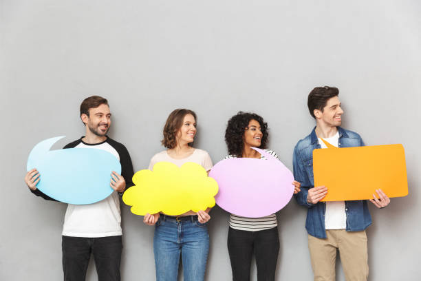 istock Happy group of friends holding speech and thoughtful bubbles. 1303885668